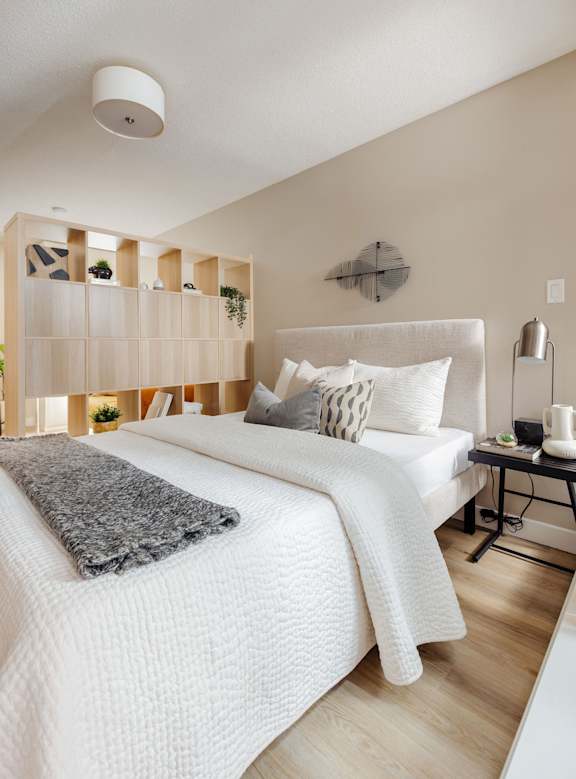 a bedroom with a white bed and a grey blanket and pillows