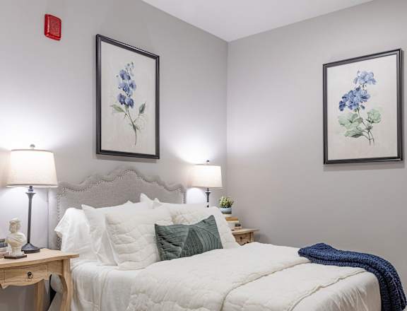 A bedroom with a white bed and a brown rug.
