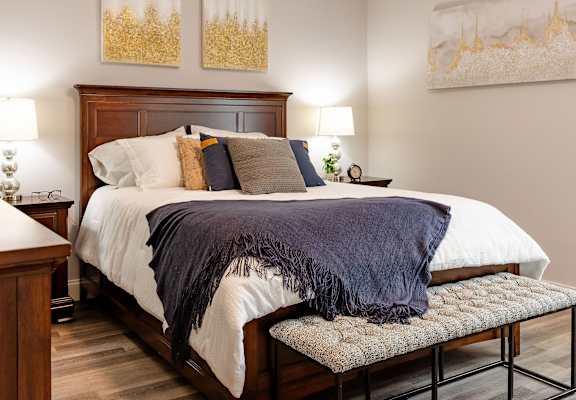 A bedroom with a bed, nightstand, and two wall art pieces.