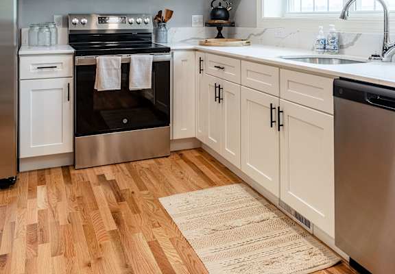 A modern kitchen with wooden floors and stainless steel appliances.