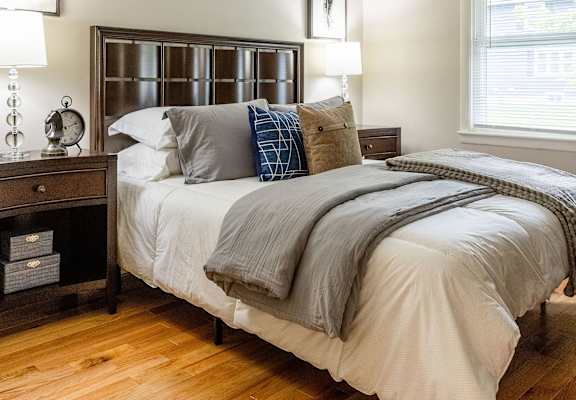 A bedroom with a bed, nightstand, and a window.