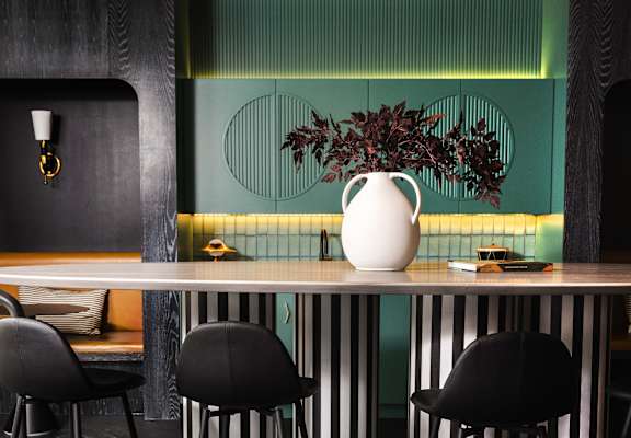 a bar with black stools and a vase with a plant