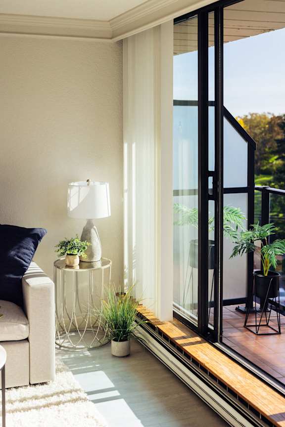 a living room with a large window and a table with plants