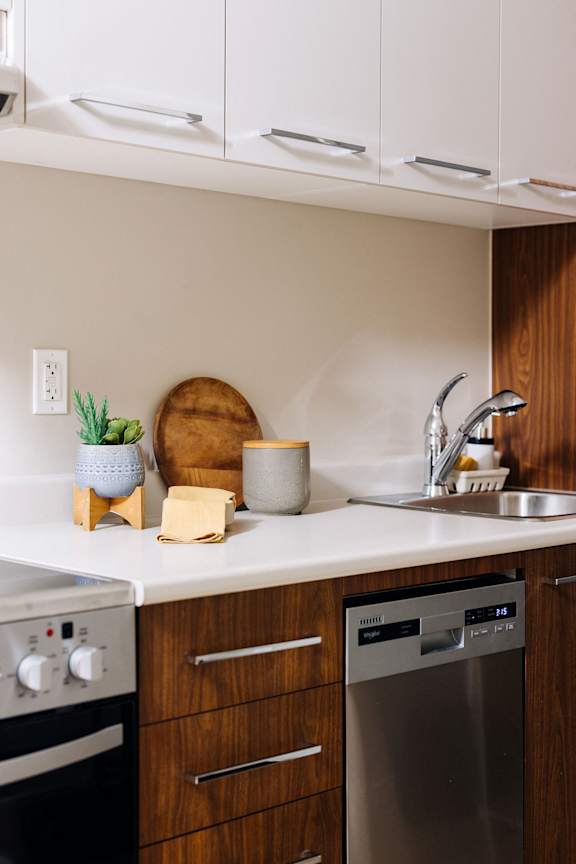 a kitchen with white counter top and wooden cabinets and a sink