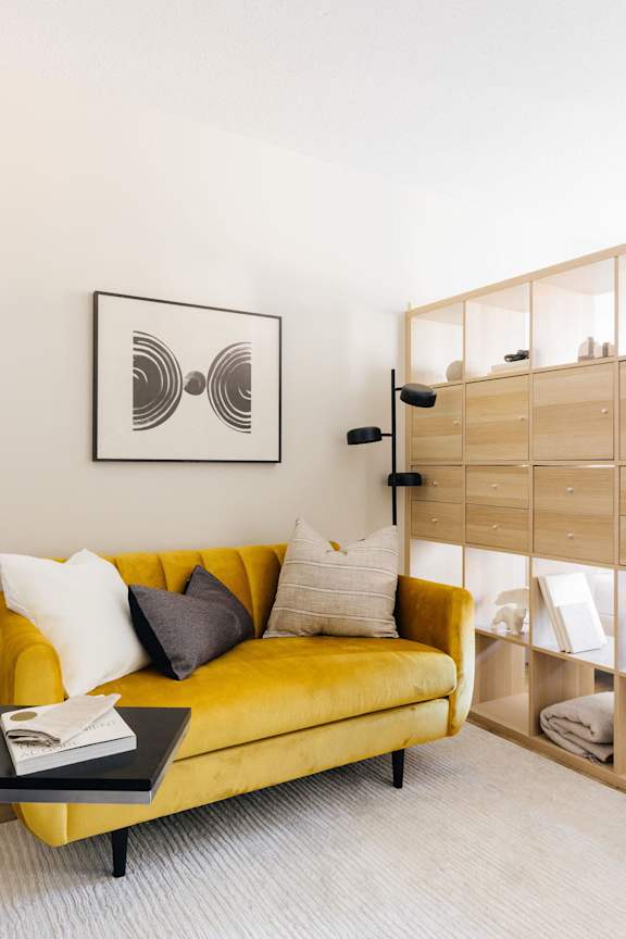 a living room with a yellow couch and a coffee table