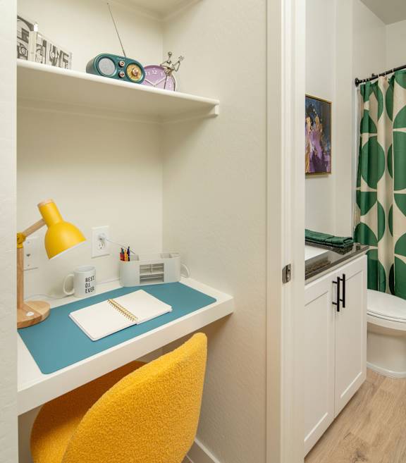 A small desk with a yellow chair in a white room.