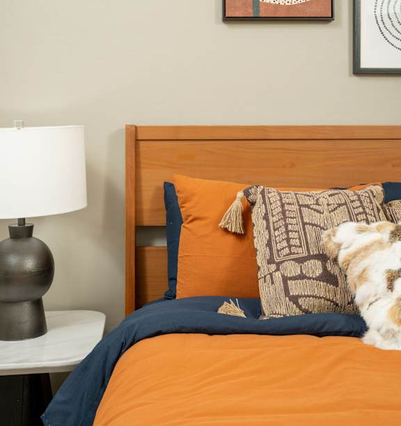 A bedroom with a bed, lamp, and pictures on the wall.
