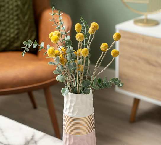 a vase with yellow flowers on a table