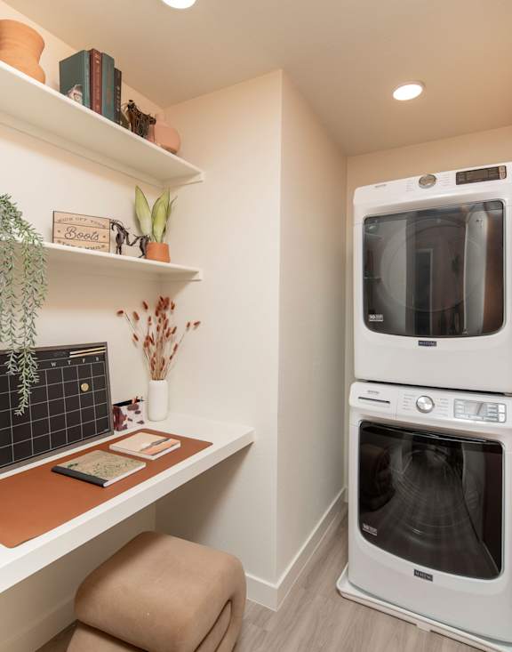 A modern kitchen with a white oven and a wooden shelf.