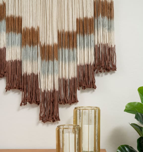 a piece of artwork hangs on a wall next to a table with two candles and a plant