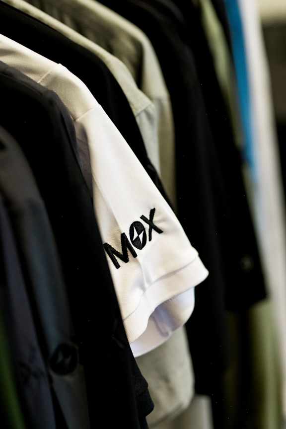 A row of clothes hanging on a rack with a white shirt in the middle.