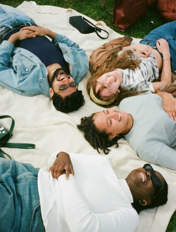 a group of people laying on a blanket on the grass