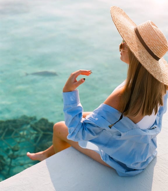 a woman sitting on a ledge looking out at the ocean