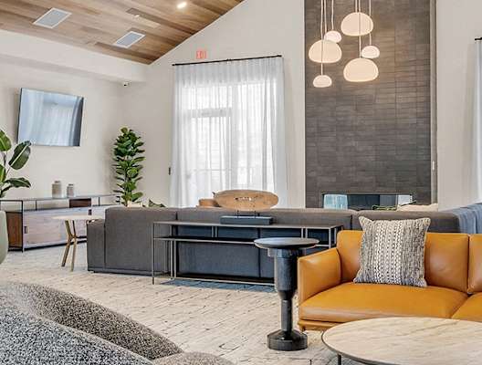 A modern living room with a grey sofa, a green armchair, a yellow sofa, a black coffee table, and a wooden side table.
