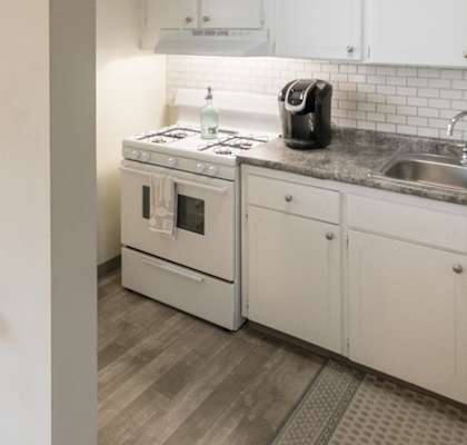 Well-lit kitchen with white cabinets, breakfast bar, and gas range in a Lake of the Woods apartment home