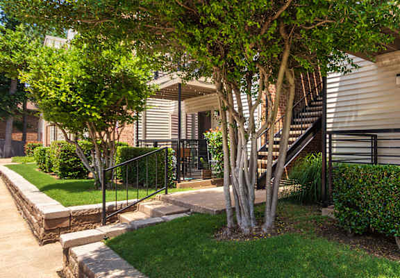 walkway past a building entrane showing some patios and landscaping at Canyon Creek Apartments in the Dallas Midtown neighborhood of Dallas, TX.