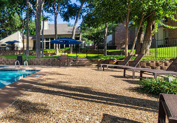 A swimming pool surrounded by trees and benches.
