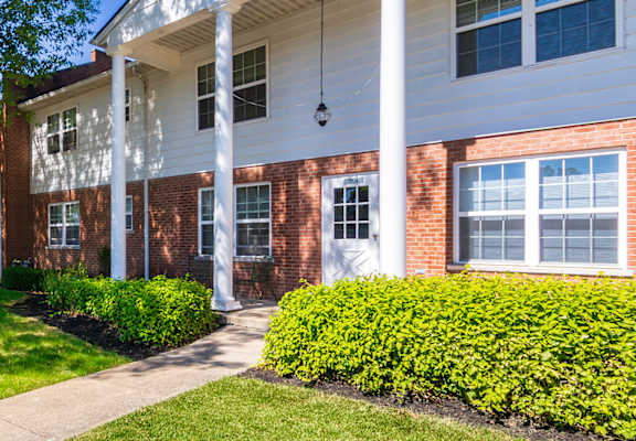 Apartment building exterior with shaded walkway and neatly maintained landscaping