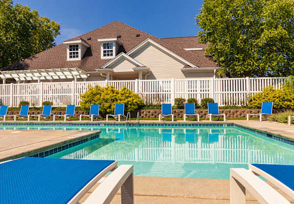 A large swimming pool with blue water and lounge chairs by thr clubhouse at Fairfield Pointe Apartments in Fairfield, Ohio.