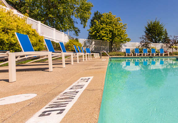 A pool surrounded by blue lounge chairs at Fairfield Pointe Apartments in Fairfield, Ohio.