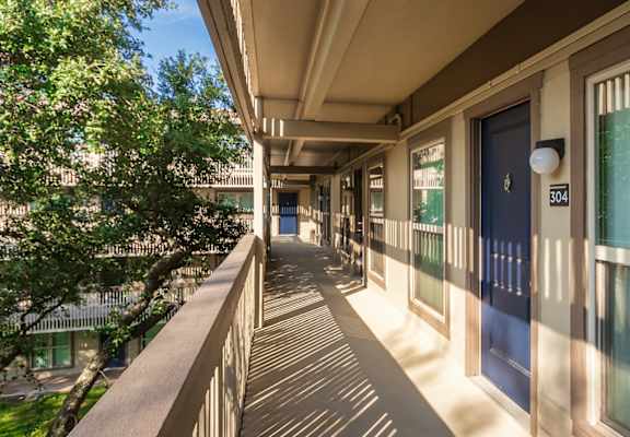 Exterior corridor with apartment entry doors and courtyard-facing walkway at Harvard Square Apartments in Vickery Midtown Dallas, TX