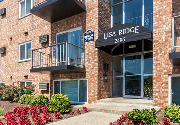 Lisa Ridge Apartments leasing office sign with landscaped flowers and brick apartment building