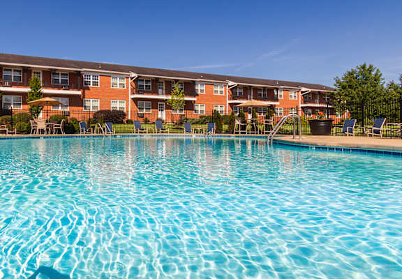 Sparkling swimming pool with handrail and apartment buildings in the background at Lake of the Woods Apartments