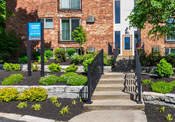 Apartment building with entrance to the leasing office and the blue leasing office sign at Romaine Court Apartments in the Oakley neighborhood of Cincinnati, Ohio.