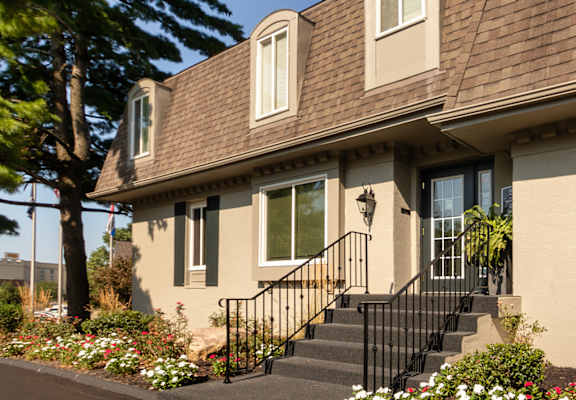 Leasing office exterior with landscaped entry and flower beds at Village East Apartments