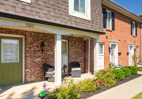 Townhome-style apartment exteriors with front patios and landscaped walkway at Village East Apartments