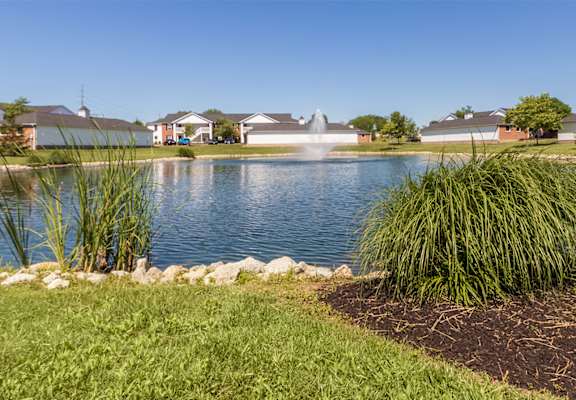 This is a photo of a pond with a fountain and building exteriors at Washington Place Apartments in Miamisburg, Ohio in Washington Township.