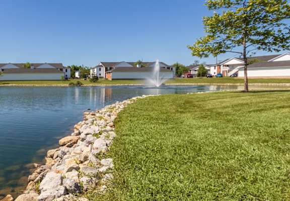 This is a photo of a pond with a fountain and building exteriors at Washington Place Apartments in Miamisburg, Ohio in Washington Township.