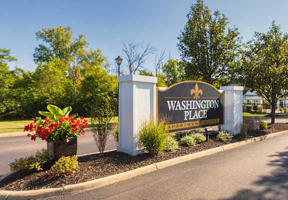 A sign for Washington Place stands at the entrance of a tree-lined street.