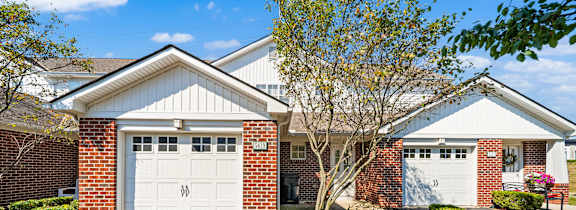 A house with a white garage door and a tree in front.