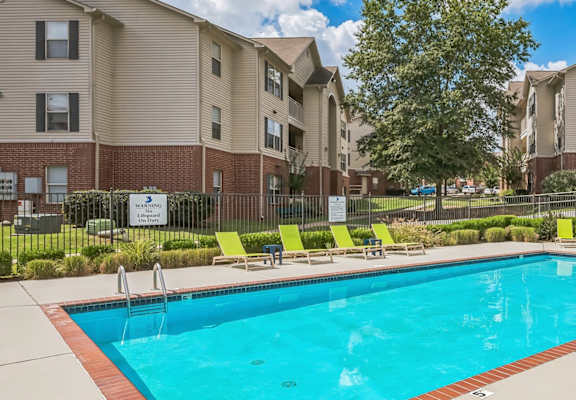 A swimming pool in a residential area with apartment buildings in the background.