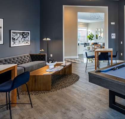 A pool table is in the middle of a room with a couch and chairs.
