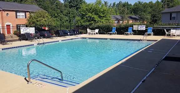a swimming pool with chairs around it in front of a house  at Brookside Pointe, Travelers Rest, SC 29690