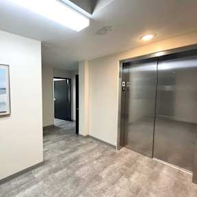 A hallway with a painting on the wall and a glass door.