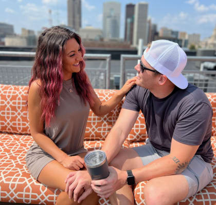 a couple sits on a couch on a rooftop with a view of the city in the background