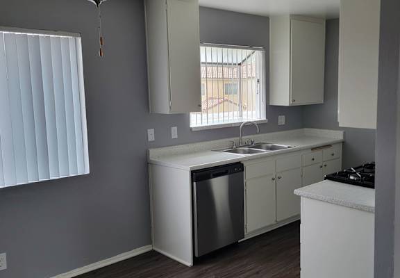 an empty kitchen with white cabinets and a stainless steel dishwasher
