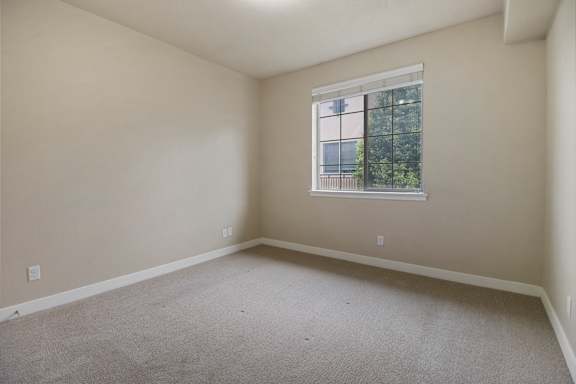 A room with a window and a view of trees outside.