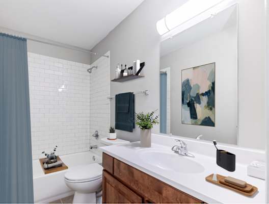 A bathroom with a white toilet, a white sink, and a white bathtub with a blue shower curtain.