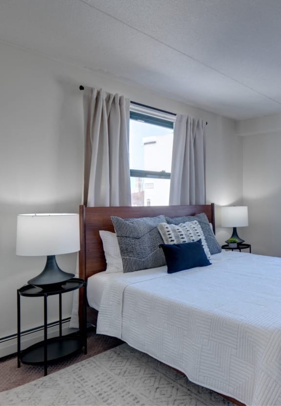 a bedroom with a large bed and two windows