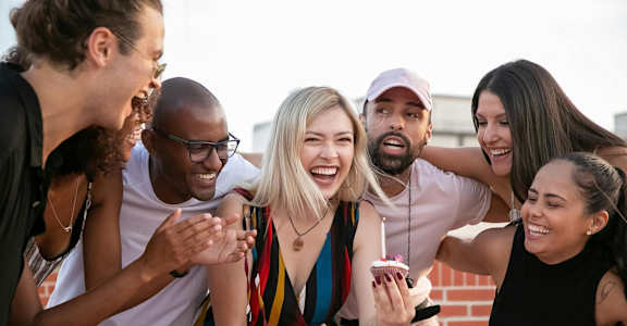 a group of friends are laughing and holding cupcakes