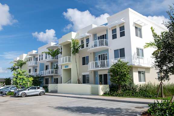 A white apartment building with a car parked in front.