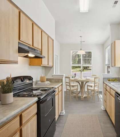 A kitchen with a black refrigerator and wooden cabinets.