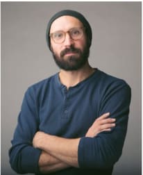 a man with a beard and glasses with his arms crossed