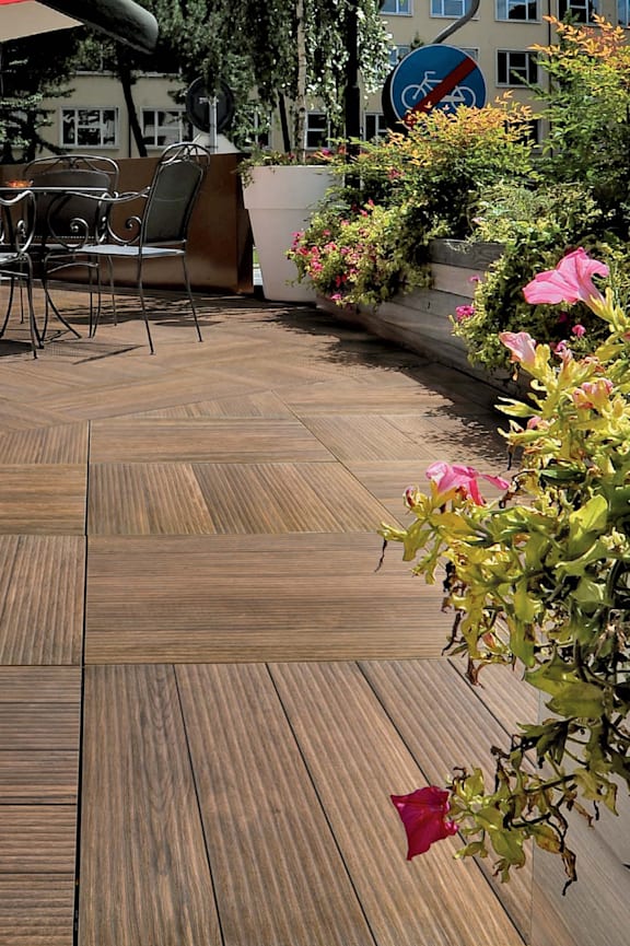 A wooden deck with a table and chairs surrounded by plants.
