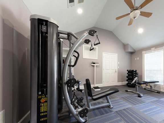 A home gym with a treadmill, weights, and a bench.