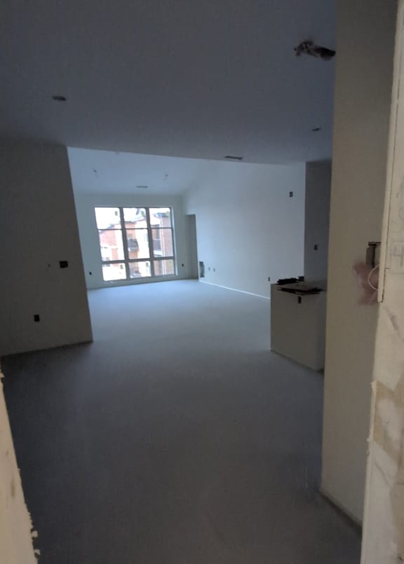 A room with a window and a white wall.